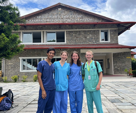 Four students standing in front of a hospital in Nepal.